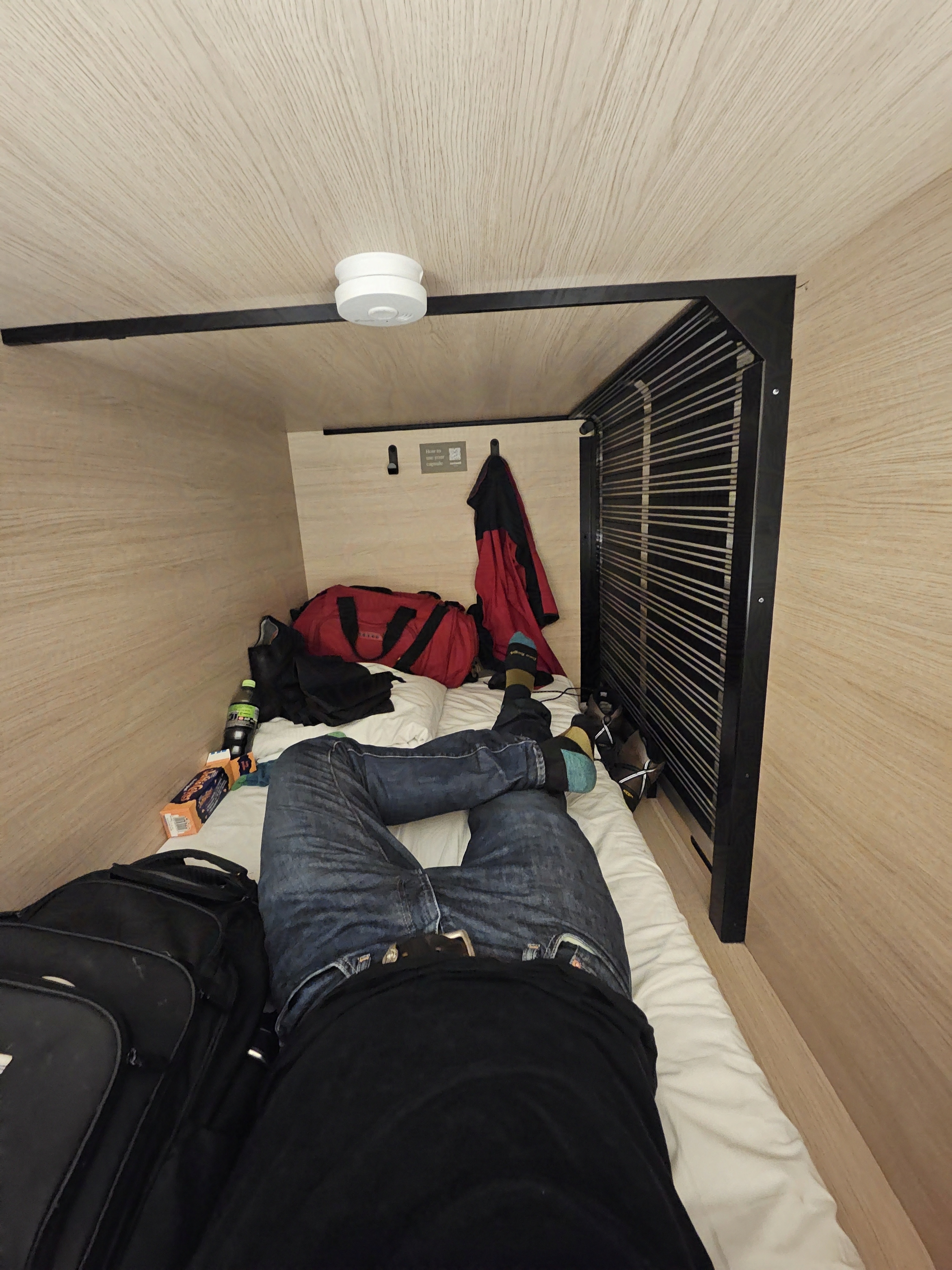 Wide angle picture of the inside of a rectangular capsule inside of a capsule hotel